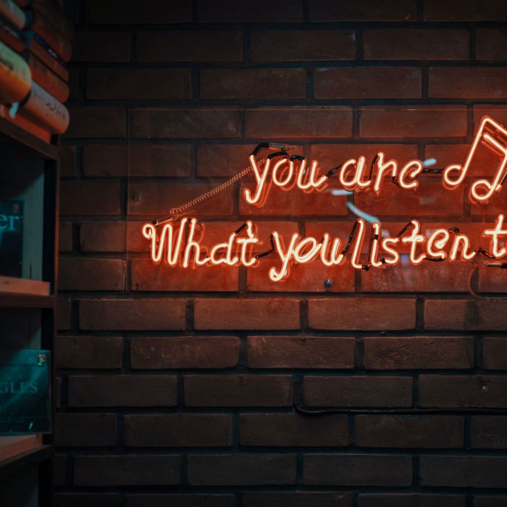 a small neon sign saying that you are what you listen to